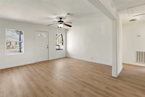 a view of empty room with wooden floor and fan