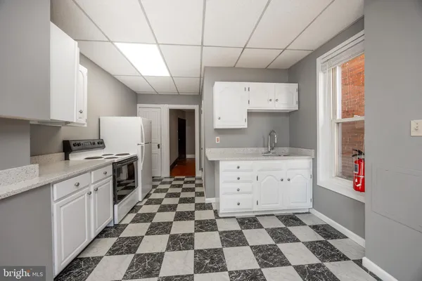 a kitchen with a checkered floor and white cabinets