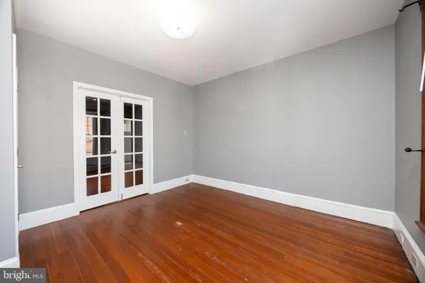a view of an empty room with wooden floor and windows