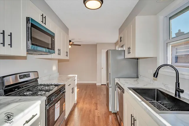 a kitchen with stainless steel appliances granite countertop a stove a sink dishwasher and microwave with wooden floor