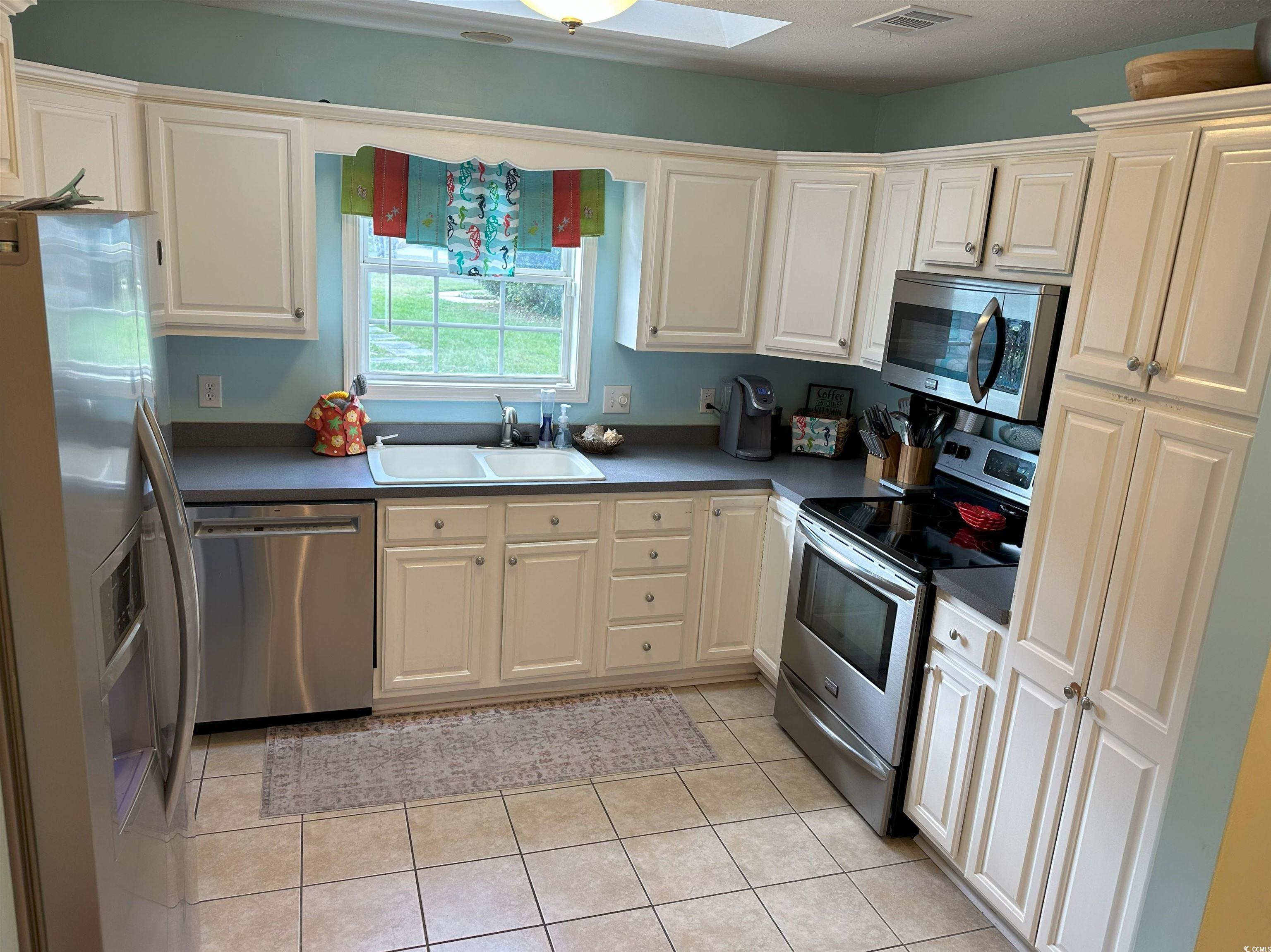 810 Marlin Court Murrells Inlet, SC 29576 - Photo 31 of 40 Kitchen with stainless steel appliances, light tile patterned flooring, dark countertops, and white cabinetry