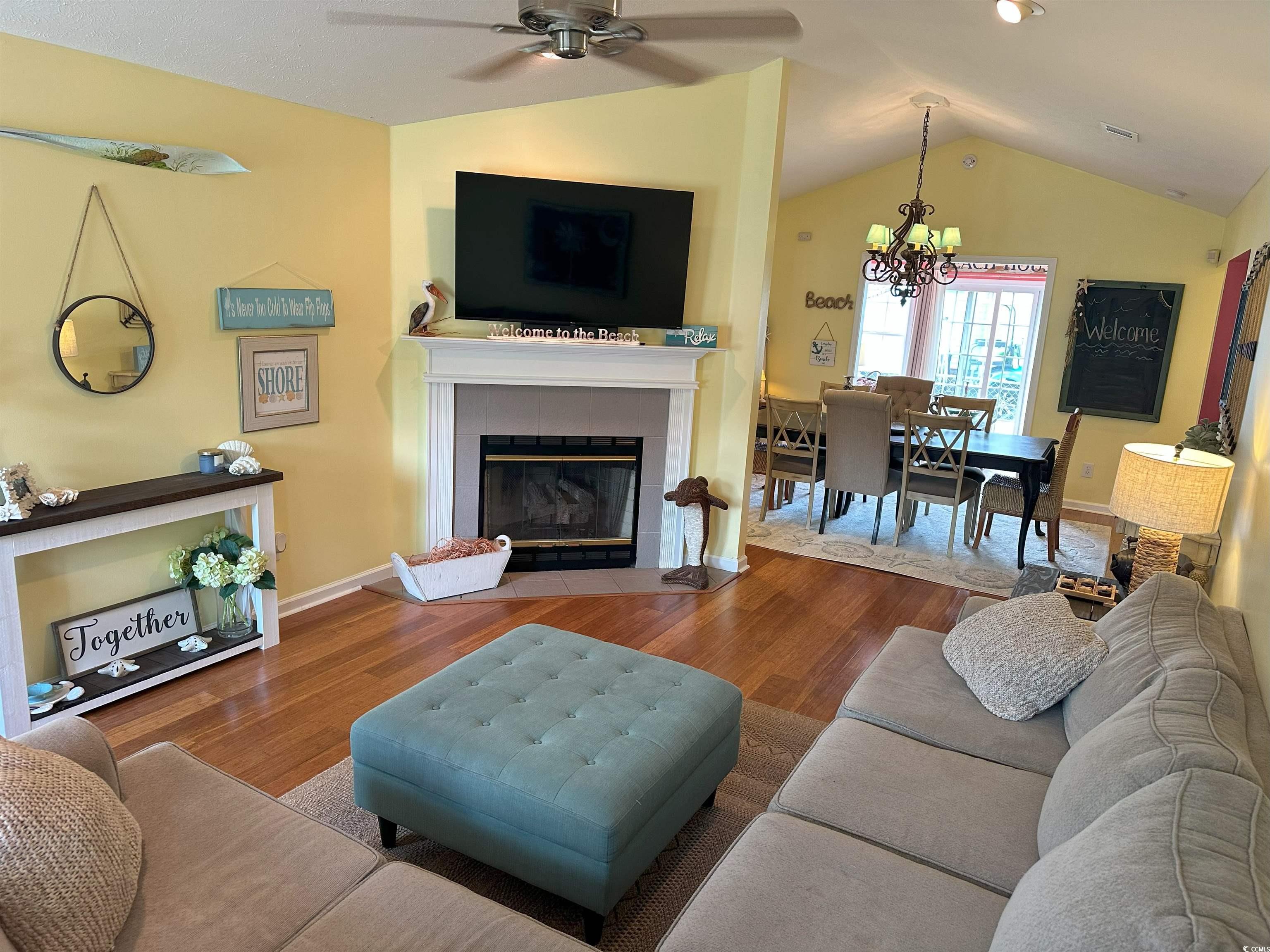 810 Marlin Court Murrells Inlet, SC 29576 - Photo 4 of 40 Living room featuring wood finished floors, a ceiling fan, a tile fireplace, vaulted ceiling, and a chandelier