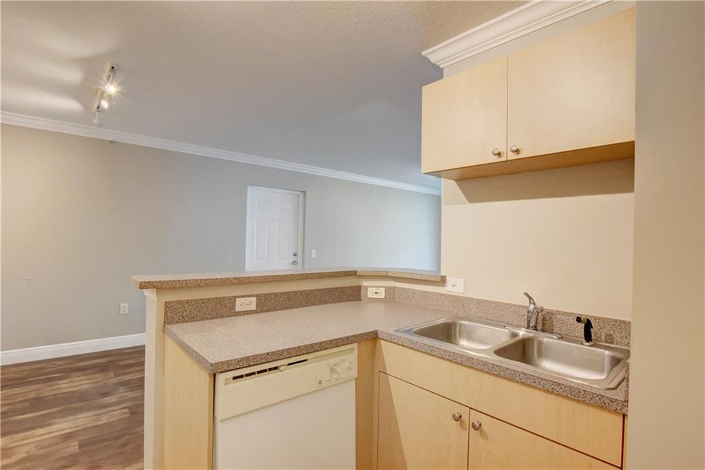 1312 Villa Lane, Unit 1312 Boynton Beach, FL 33435 - Photo 5 of 34 a view of a sink and dishwasher with wooden cabinet