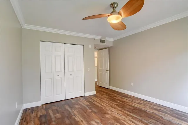 a view of an empty room with wooden floor and windows