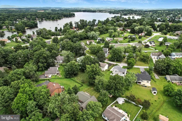 an aerial view of a residential houses with outdoor space and trees all around