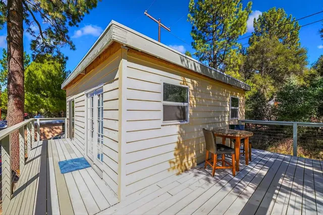 a balcony with wooden floor and trees in the back