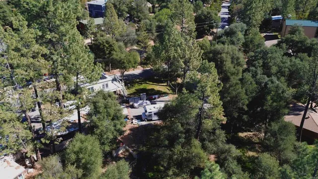 an aerial view of a residential house with green field and mountains