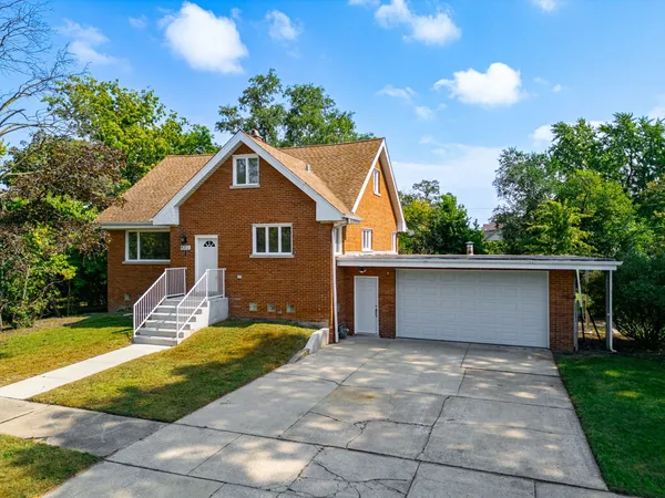 a front view of house with yard and trees in the background