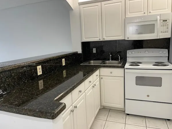a kitchen with granite countertop white cabinets and black appliances