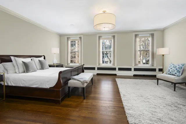 a spacious bedroom with a bed a chandelier and windows