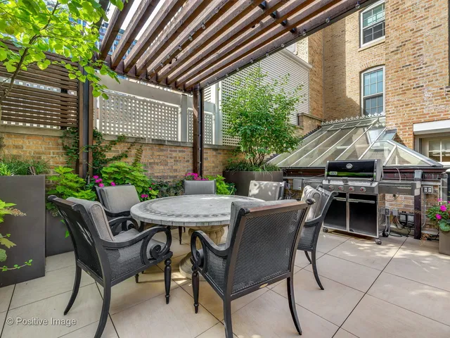 a view of a patio with a table and chairs and a barbeque