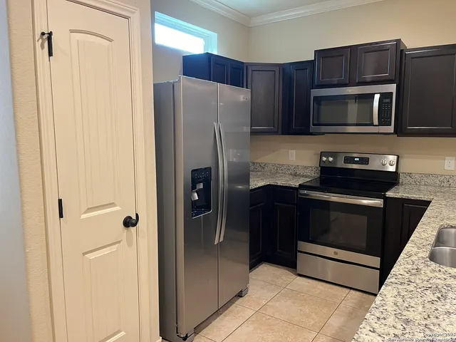 a kitchen with stainless steel appliances granite countertop a refrigerator and a stove top oven