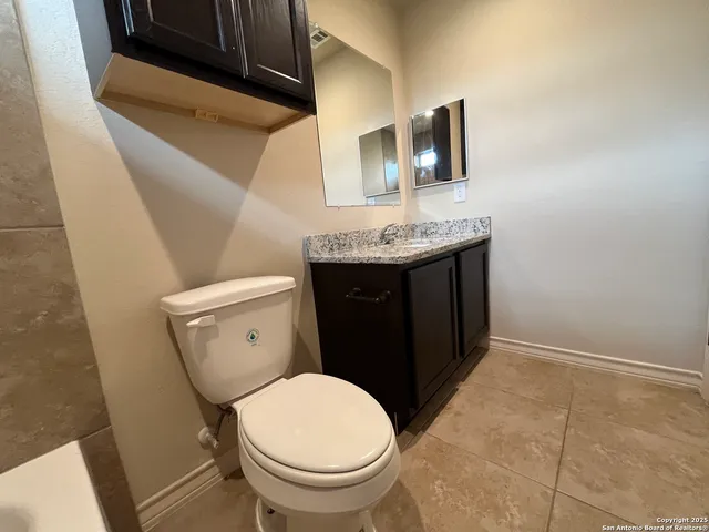 a bathroom with a granite countertop toilet and a sink