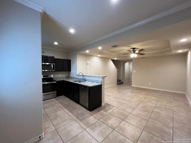 a large kitchen with a large counter top space appliances and a ceiling fan
