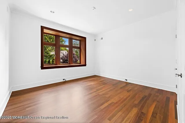 a room with wooden floor pool table and windows