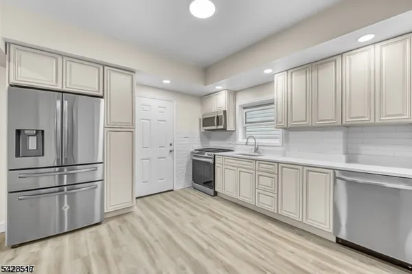 a kitchen with white cabinets stainless steel appliances and window