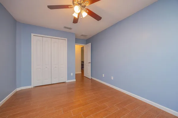 an empty room with closet and a chandelier fan