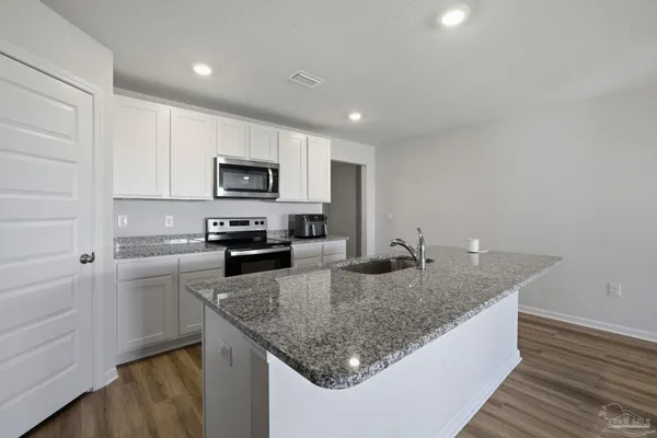 a kitchen with granite countertop kitchen island a counter space a sink and appliances