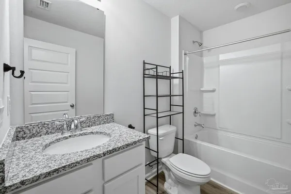 a bathroom with a granite countertop sink toilet mirror and shower