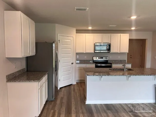 a kitchen with kitchen island granite countertop a refrigerator stove top oven and sink