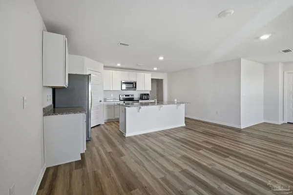 a view of kitchen with cabinets stainless steel appliances and wooden floor
