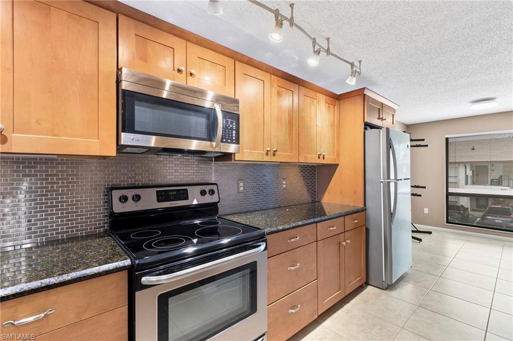 236 Pebble Beach Circle, Unit A202 Naples, FL 34113 - Photo 8 of 25 a kitchen with kitchen island granite countertop a sink cabinets and stainless steel appliances
