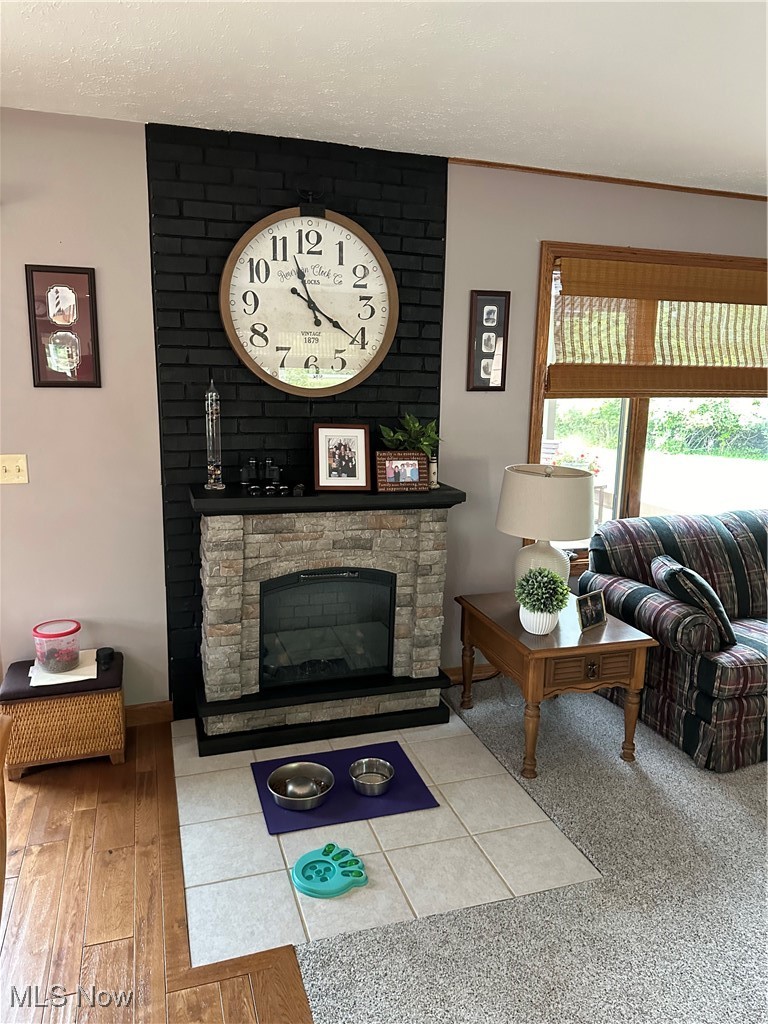 354 Big Bass Road Willard, OH 44890 - Photo 15 of 29 Living room featuring a stone fireplace, wood-type flooring, brick wall, and a textured ceiling