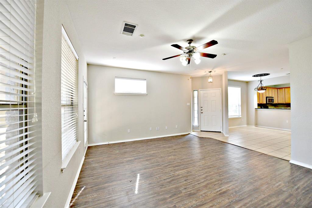 14815 Avery Ranch Boulevard, Unit 702 Austin, TX 78717 - Photo 5 of 19 Unfurnished living room with wood finished floors, visible vents, baseboards, and ceiling fan