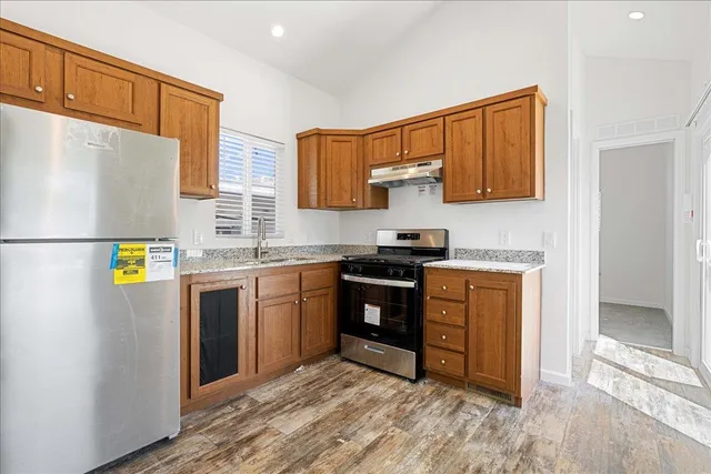 a kitchen with stainless steel appliances granite countertop a refrigerator a stove top oven a sink and dishwasher