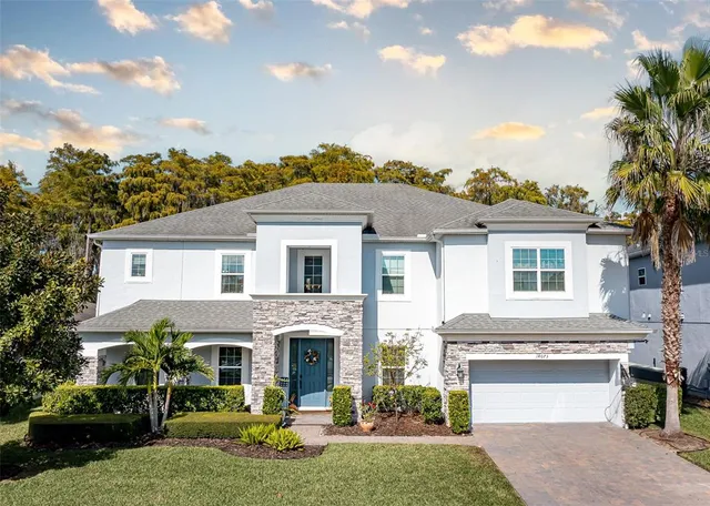 a aerial view of a white house next to a yard with plants and large trees