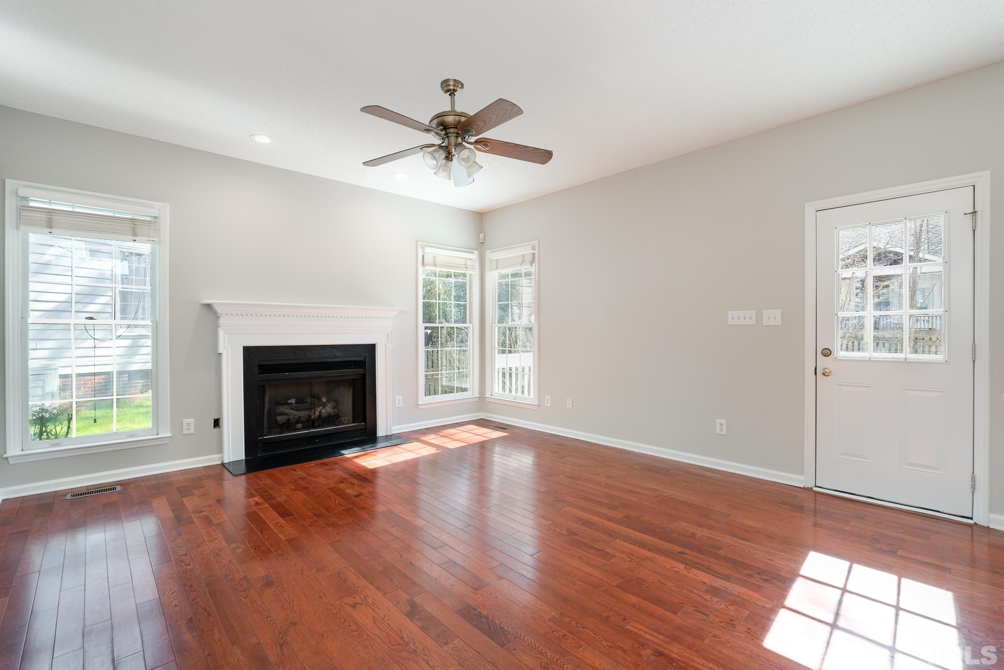 5209 Halcott Court Raleigh, NC 27613 - Photo 7 of 25 a view of an empty room with wooden floor fireplace and a window