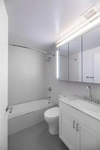 a bathroom with a granite countertop sink a toilet and bathtub