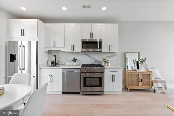 a kitchen with white cabinets and stainless steel appliances