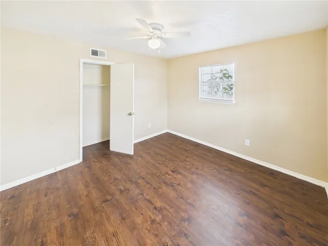an empty room with wooden floor and ceiling fan