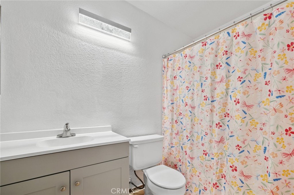 129 Avocado Avenue Perris, CA 92571 - Photo 19 of 30 a bathroom with a sink a toilet and shower curtain