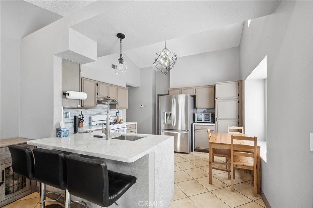 129 Avocado Avenue Perris, CA 92571 - Photo 10 of 30 a kitchen with stainless steel appliances kitchen island granite countertop a table chairs and a refrigerator