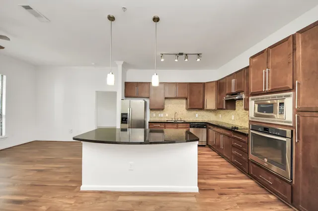 a large kitchen with stainless steel appliances granite countertop a stove a sink and a refrigerator