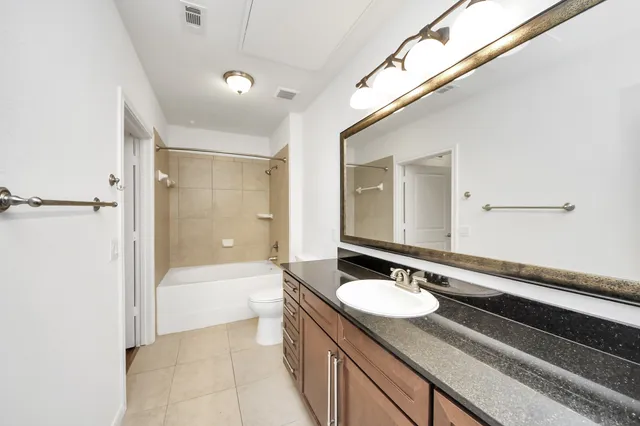 a bathroom with a granite countertop sink a mirror a bathtub and shower