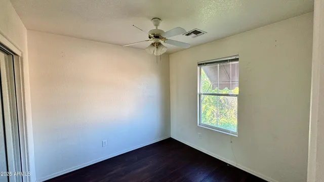 an empty room with wooden floor fan and windows