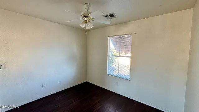 an empty room with a window and a chandelier fan