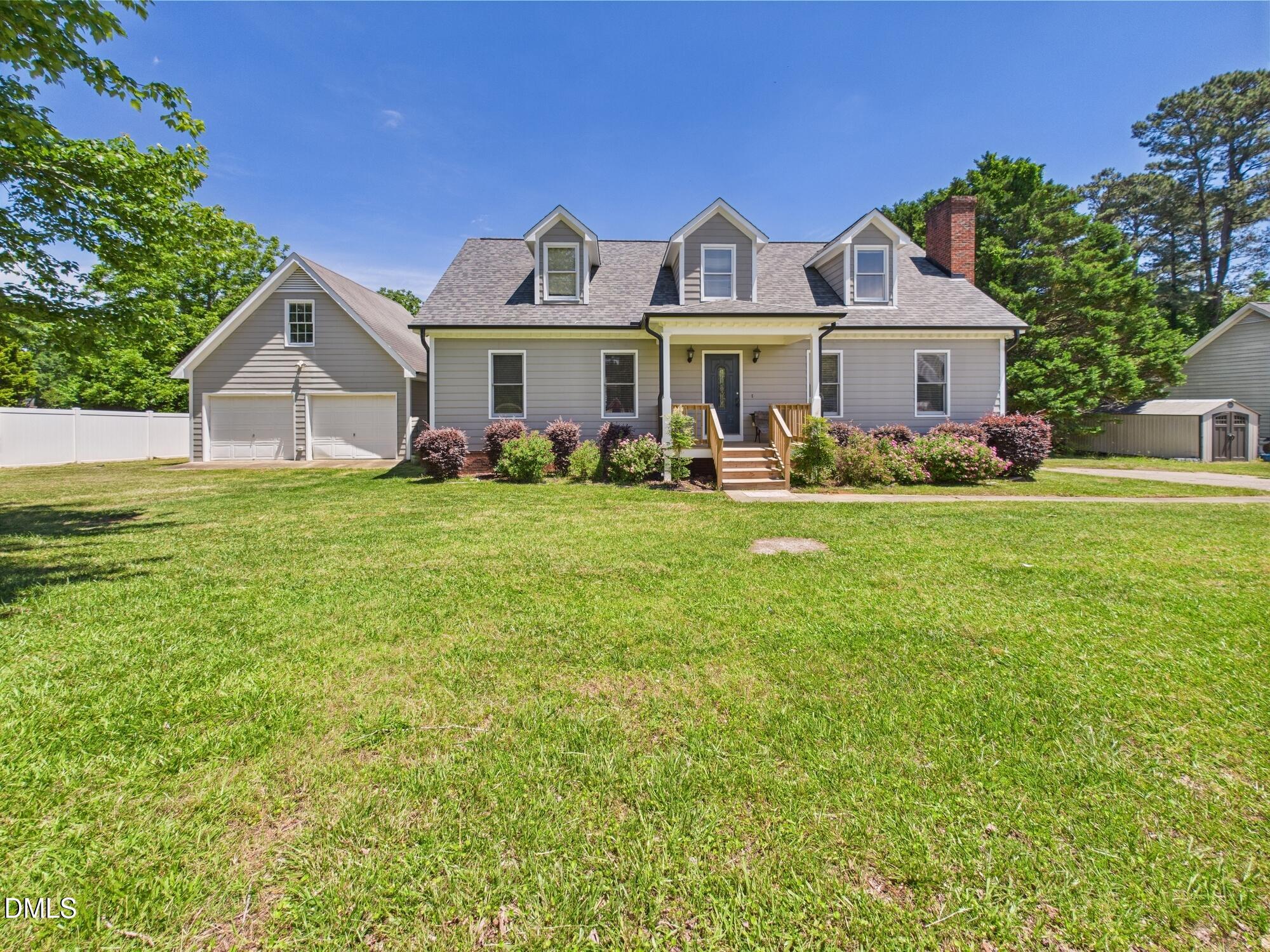 a front view of a house with a garden and trees