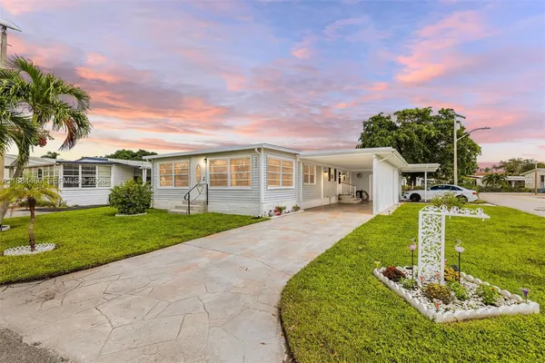a hall with kitchen island granite countertop a sink cabinets window and stainless steel appliances