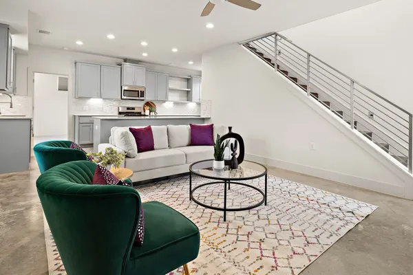 a living room with furniture kitchen view and a chandelier