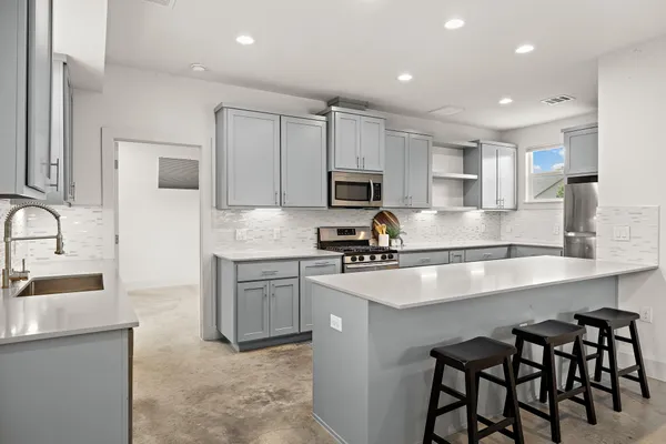 a kitchen with kitchen island granite countertop a sink counter top space appliances and cabinets