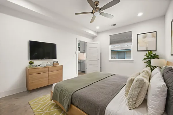 a bedroom with a bed television on dresser and a window