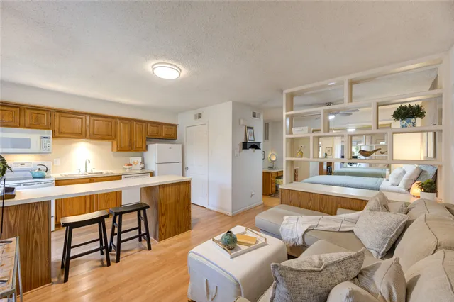 a living room with stainless steel appliances kitchen island granite countertop furniture and a wooden floor