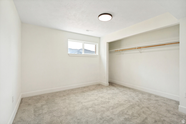 62 South Clark Lane Elk Ridge, UT 84651 - Photo 23 of 30 Neutral-toned large 4th bedroom featuring a window with a mountain backdrop, plush grey carpeting, and an open closet with a single hanging rod