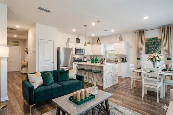 a living room with furniture a kitchen view and a refrigerator