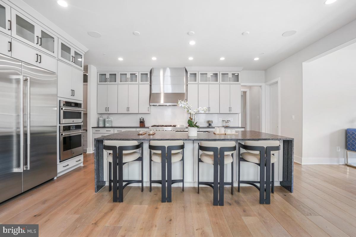 12321 Potomac Hunt Road North Potomac, MD 20878 - Photo 17 of 64 a kitchen with kitchen island granite countertop wooden floors and chairs
