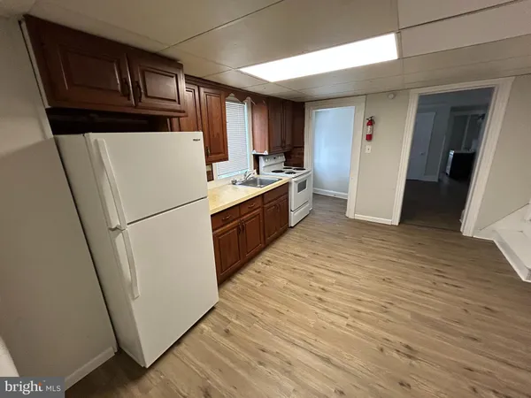 a kitchen with sink a refrigerator and wooden floor